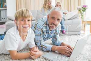 Father and son using laptop on the floor