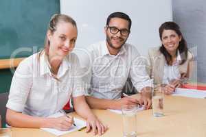 Smiling business people taking notes during meeting