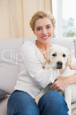 Happy blonde cuddling with puppy on sofa