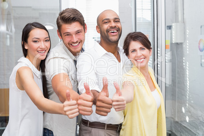 Business people giving thumbs up to camera and smiling