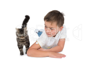 Cute boy looking at grey kitten lying on floor