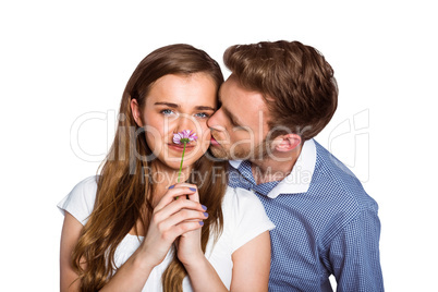 Man kissing woman as she holds flower