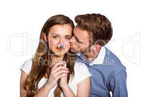 Man kissing woman as she holds flower