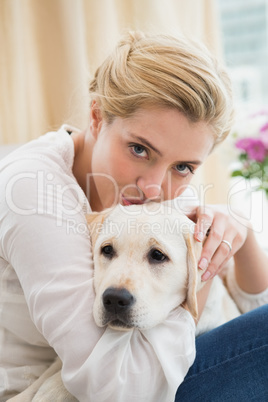 Happy blonde cuddling with puppy on sofa