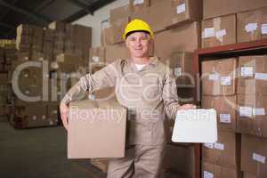 Delivery man with box and clipboard in warehouse