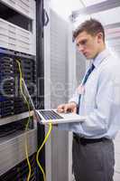 Technician using laptop while analysing server