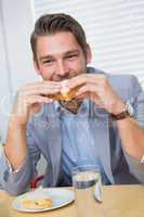 Smiling businessman eating a sandwich