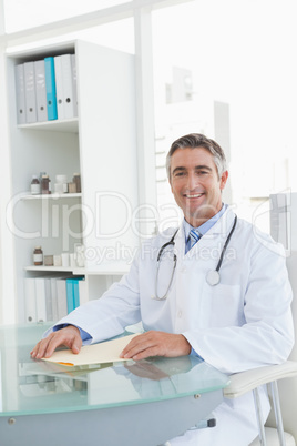 Cheerful doctor sitting at his desk