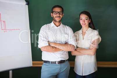 Two confident business people with arms crossed in office