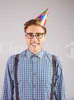 Geeky hipster wearing party hat smiling at camera