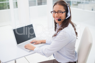 Smiling businesswoman using laptop at her desk