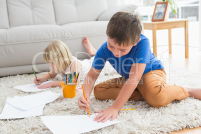 Smiling siblings drawing lying on the floor