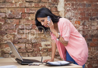 Woman calling with her mobile phone and looking at diary