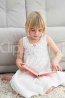 Little girl sitting on the floor reading storybook
