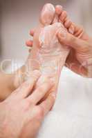 Pedicurist covering customers foot in soap