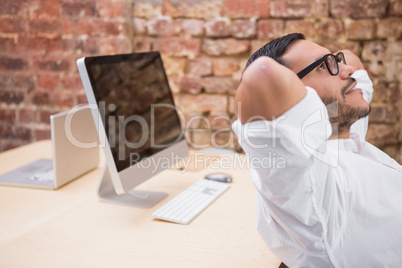 Businessman with hands behind head in office