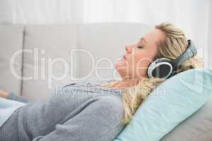 Happy girl listening to music lying on the couch