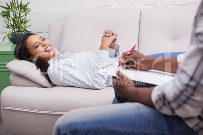 Woman lying on the couch while psychologist writing