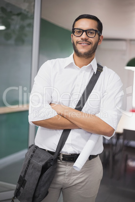 Casual architect smiling at camera holding blueprint