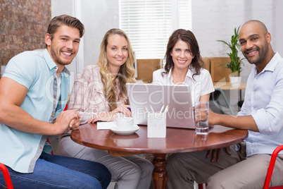 Smiling business team working together with laptop