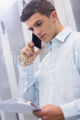 Young technician calling and reading a document