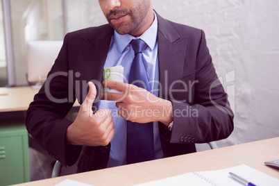 Mid section of businessman keeping currency in pocket