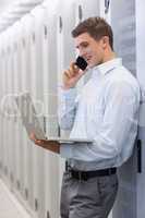 Smiling technician phoning and using his notebook