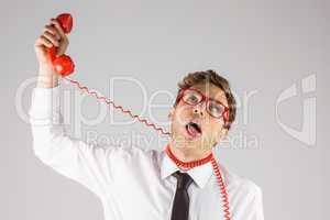 Geeky businessman strangling himself with telephone