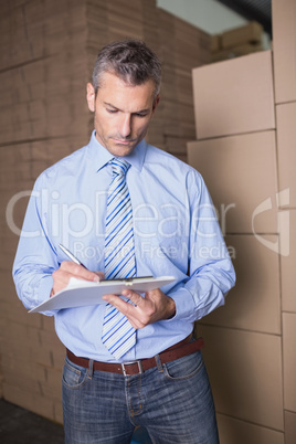 Manager with clipboard in warehouse