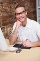 Smiling man with hand on chin drawing on graphic tablet