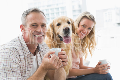 Smiling casual couple sitting on couch having coffee