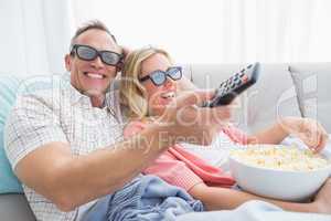 Happy couple wearing 3d glasses eating popcorn