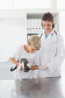 Smiling vet examining a cat with its owner