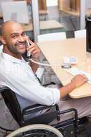 Businessman in wheelchair phoning and smiling at camera