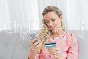 Woman looking at her credit card holding phone