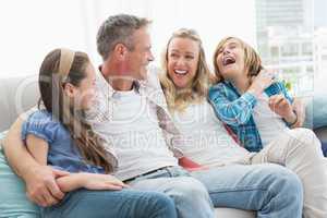 Smiling parents and children sitting together on couch