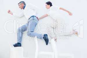 Business partners jumping over chairs
