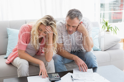 Worried couple calculating bills on the couch