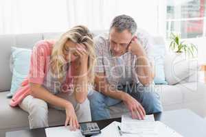 Worried couple calculating bills on the couch