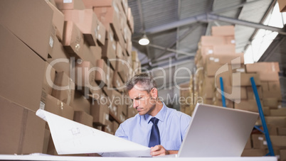 Warehouse manager looking at blueprint