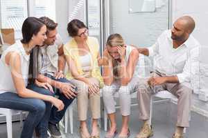 Business team sitting together supporting sad colleague