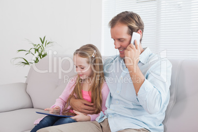 Casual father and daughter using tablet on the couch