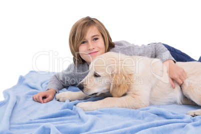 Child rubbing his dog lying on a blanket