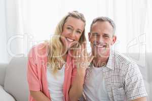 Happy woman showing engagement ring besides man