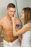 Cute woman putting cream on boyfriends nose