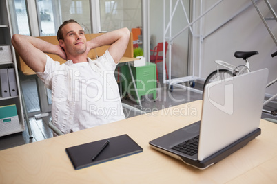 Man sitting with hands behind head at desk