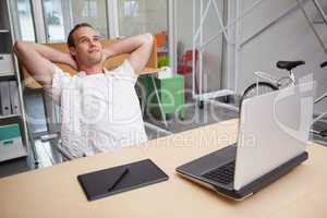 Man sitting with hands behind head at desk