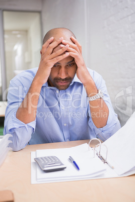 Tired businessman with paperwork at desk