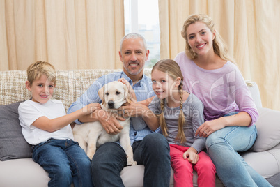 Parents with their children on sofa playing with puppy