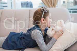 Little girl lying on the couch with teddy